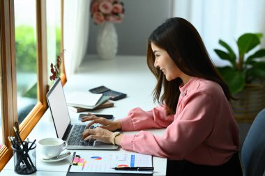 Modern ofiste yatırım ve pazarlama projeleri üzerinde çalışan güzel Asyalı kadın girişimci.
