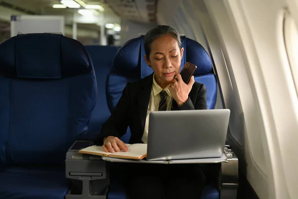 ビジネス旅行中に航空機で文書を扱う美しい中年ビジネスマン — ストック写真