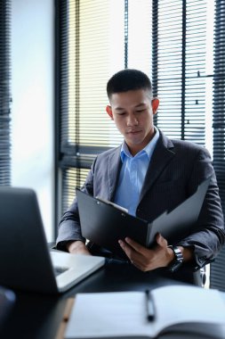 Modern işyerinde ekonomi raporunu hazırlayan grafikleri ve grafikleri analiz eden odaklanmış bin yıllık iş adamı..