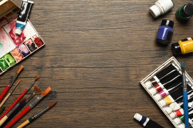 Akrilik, boş uzay metniyle ahşap zemin üzerinde tüpler, paletler ve fırçalar boyar. Sanat, eğitim ve yaratıcılık kavramı..