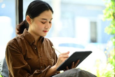 Modern ofis çalışma alanında dijital tablet kullanan Asyalı kadın..