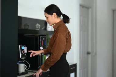 Ofiste kahve makinesi kullanan Asyalı iş kadını...