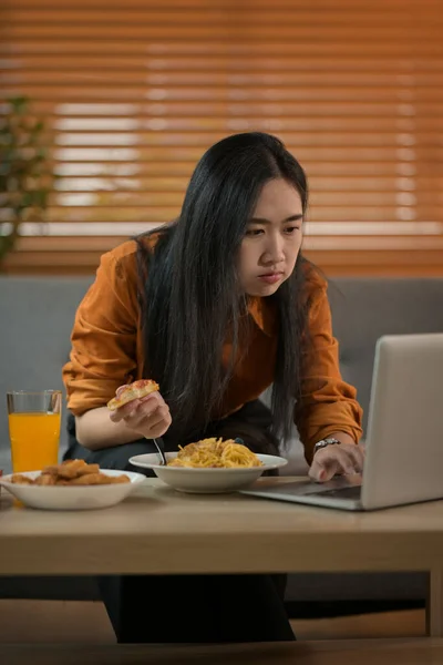 Ασιάτισσα Γυναίκα Τρώει Μακαρόνια Και Φορητό Υπολογιστή Στο Τραπέζι Εργάζεται — Φωτογραφία Αρχείου