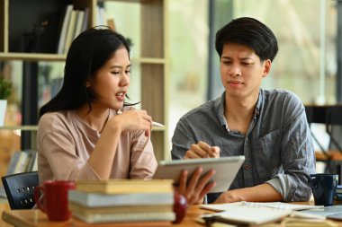 İki dost canlısı üniversite öğrencisi dizüstü bilgisayarla masada oturmuş, araştırmayı tartışıyorlar, görevleri birlikte öğreniyorlar...