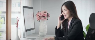 Zeki Asyalı iş kadını cep telefonuyla konuşuyor, iş ortağı modern işyeriyle pazarlık ediyor.. 
