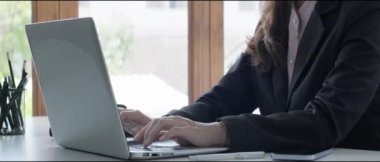 Siyah takım elbiseli genç iş adamı laptopta yazı yazıyor..