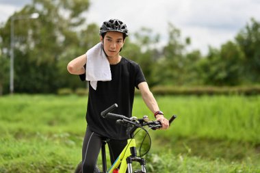 Terleyen, bisiklete binip parkta bisiklet sürmeye ara veren yorgun bir bisikletçinin görüntüsü..