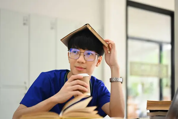 Φοιτητής Ιατρικής Φοράει Μπλε Ποδιά Βάζει Βιβλίο Στο Κεφάλι Και — Φωτογραφία Αρχείου