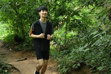 Yeşil bir ormanda koşan adamlar. Spor motivasyonu, macera, sağlıklı yaşam tarzı.