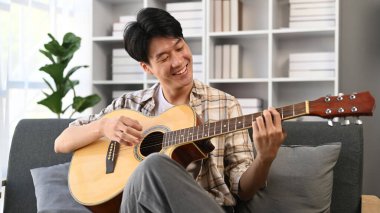 Evde gitar çalan bir adam. Ev hayatı kavramı..