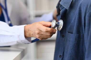 Doktor steteskop kullanıyor, hastanın nefesini ya da kalp atışlarını dinliyor. Sağlıklı bakım, ilaç ve sigorta konsepti.