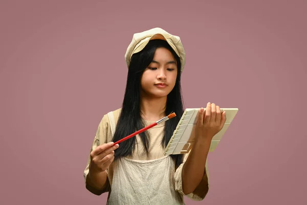 Aranyos Ázsiai Lány Kötényt Visel Egy Festékpalettával Ecsettel Izolált Rózsaszín — Stock Fotó