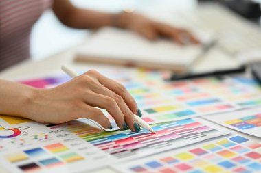 Masadaki yeni tasarım projesi için renk örnekleri grafiği ile çalışan tasarımcının yakın plan içeceği.