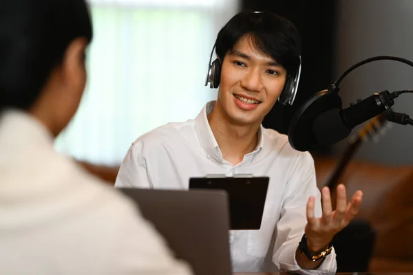 Sorridente Asiatico Ospite Radio Maschile Indossa Cuffie Intervistando Ospite Registrazione — Foto Stock