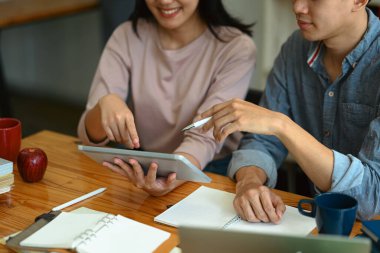 Üniversite öğrencileri dijital tablet kullanıyorlar, kampüsteki bir projede işbirliği yapıyorlar. Eğitim ve teknoloji kavramı.