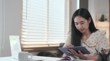 Günlük giysiler içinde mutlu kadın serbest yazar gülen yüzlü dijital tablete bir şeyler yazıyor..