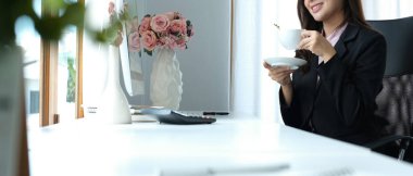 Rahat kadın işçi çay içiyor ve ofis penceresinden dışarı bakıyor, teneffüste boş zamanlarının tadını çıkarıyor..