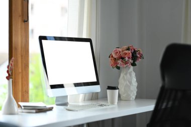 Klavyeli boş bir bilgisayar, beyaz ofis masasında bir fincan kahve ve kitaplar. Modern işyeri.