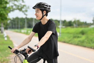 Kırsalda bisiklet süren yakışıklı Asyalı genç bir adam. Seyahat, spor ve aktif yaşam tarzı konsepti..