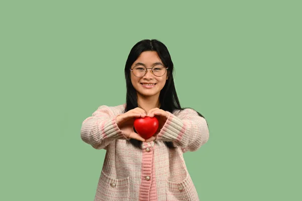 Усміхнена Азіатська Дівчина Підліток Тримає Червоне Серце Ізольовано Зеленому Тлі — стокове фото