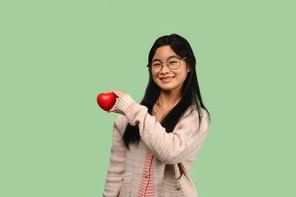 Усміхнена Азіатська Дівчина Підліток Тримає Червоне Серце Ізольовано Зеленому Тлі — стокове фото