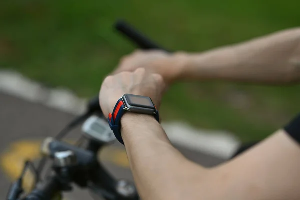 Cropped image of man cyclist sitting on his bicycle and checking sport activity progress data on smartwatch..