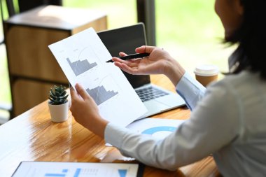 Modern iş yerinde grafik ve çizelgeleri analiz eden kadın finansörlerin yan görünümü.