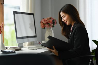 İş yerinde oturup mali raporları kontrol eden güzel bayan yöneticinin yan görüntüsü.