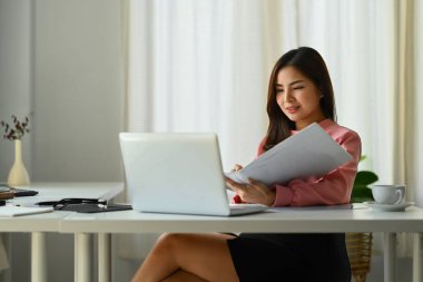 Güzel Asyalı iş kadını bilgisayarını kullanarak ofisinde yeni bir başlangıç projesi üzerinde çalışıyor..