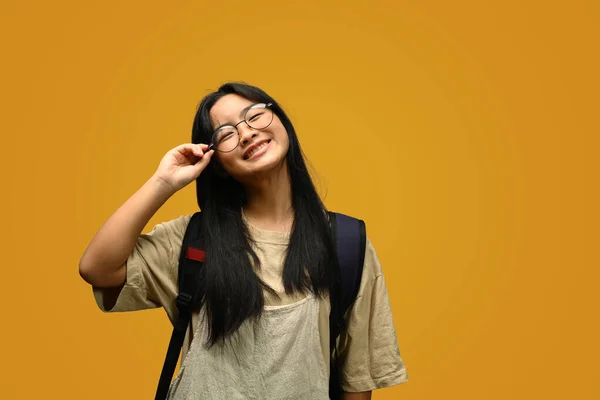 Sarı Arka Planda Duran Sırt Çantalı Gözlüklü Gülümseyen Liseli Kız — Stok fotoğraf