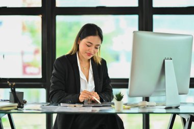 Finansal piyasa verileriyle çalışan ve ofiste dijital tablet kullanan güzel bir iş kadını.