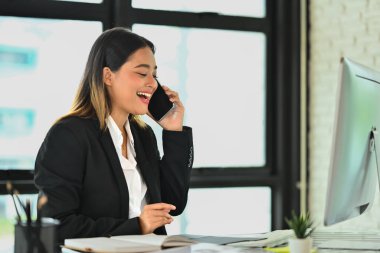 Mutlu Milenyum kadın satış temsilcisi siyah takım elbiseli yönetici müşteriyle cep telefonunda konuşuyor...