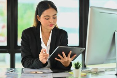 Dijital tablet kullanan Asyalı iş kadını finans piyasası veri kurumuyla çalışıyor..