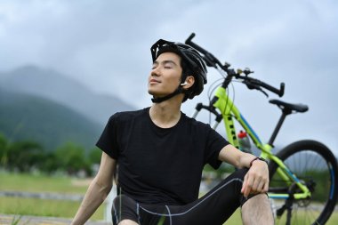 Gülümseyen bisikletçi gözleri kapalı temiz hava soluyor ve sabah sporundan sonra dinleniyor...