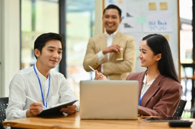 İş ekibi laptop ekranına bakıyor. Modern kurumsal ofiste önemli bir proje için beyin fırtınası yapıyorlar..