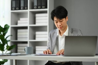 Ofis masasında oturan işadamı, modern ofiste yeni başlatılan projeyle çalışıyor..