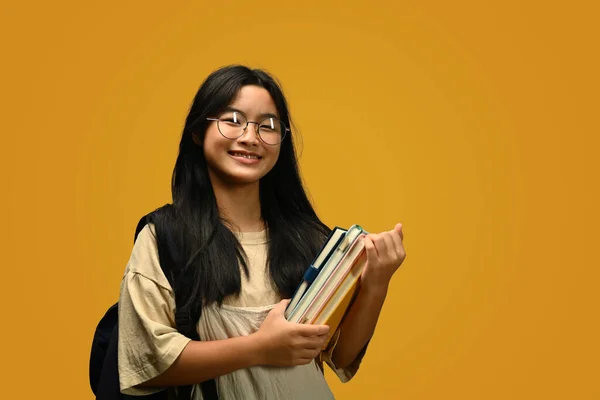 笑容满面的少女背着书包站在黄色的背景上 回到学校的概念 — 图库照片