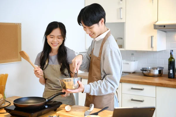 ハンサムなアジアの男は居心地の良いキッチンで彼の妻と朝食を準備しながらパンケーキのための生地を混合する手 — ストック写真