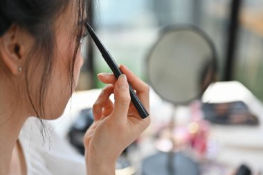 Kaşlarını kalemle çizen genç bir kadının yan görüntüsü. Güzellik makyaj konsepti.