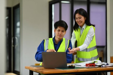 İnşaat mühendisi ekibi beyin fırtınası yapıyor, inşaat ofisinde gelişim detayları planlıyor.