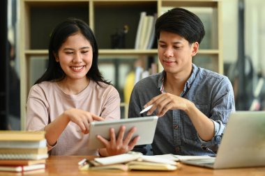 İki mutlu Asyalı öğrenci ödev tartışıyorlar, kütüphanede ortak çalışma projesi üzerine beyin fırtınası yapıyorlar..