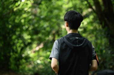 Yeşil bir ormanda koşan erkek izlerinin arka görüntüsü. Spor motivasyonu, macera, sağlıklı yaşam tarzı.