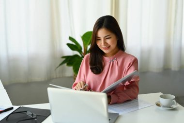 Güzel iş kadını pazarlama verilerini, istatistikleri ve mali sonuçları masasında analiz ediyor..