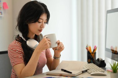 Çekici, genç, serbest çalışan, kahve içen, rahat bir iş yerinde işe ara veren bir kadın..