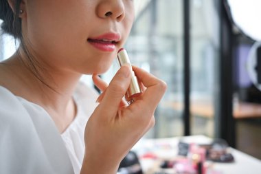 Evde aynanın önünde dudaklarına ruj süren genç bir kadın. Güzellik kozmetik, makyaj ve blog yazarı.