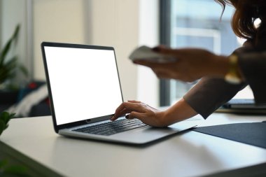 Elinde hesap makinesiyle ofis masasında dizüstü bilgisayar kullanan kadın muhasebeci görüntüsü..