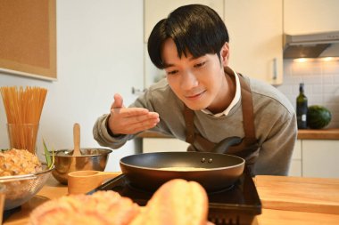 Kızartma tavasında leziz krep kokan, mutfak tezgahında sağlıklı yemek hazırlayan mutlu bir adam..