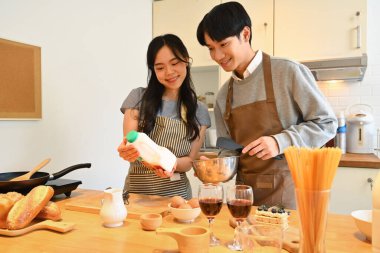 Mutlu genç çift güzel bir sabahta mutfakta krep için hamur hazırlıyor. Aşçılık, ilişki ve ev hayatı.