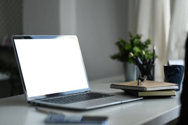 Boş ekran, not defteri ve gözlüklü dizüstü bilgisayarı beyaz ofis masasında kapat.