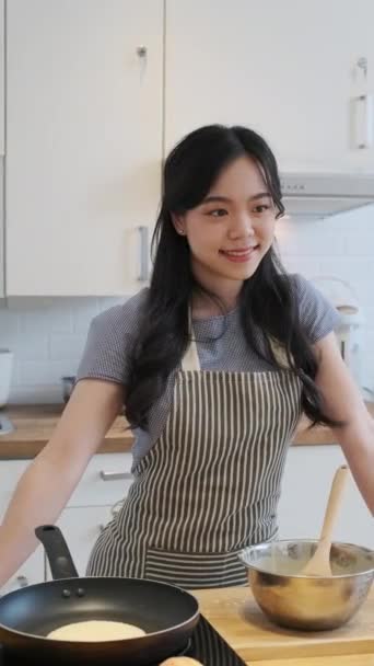ホームキッチンで一人で立っている美しいアジアの若い女性のスローモーションショット 笑顔カメラを見る — ストック動画